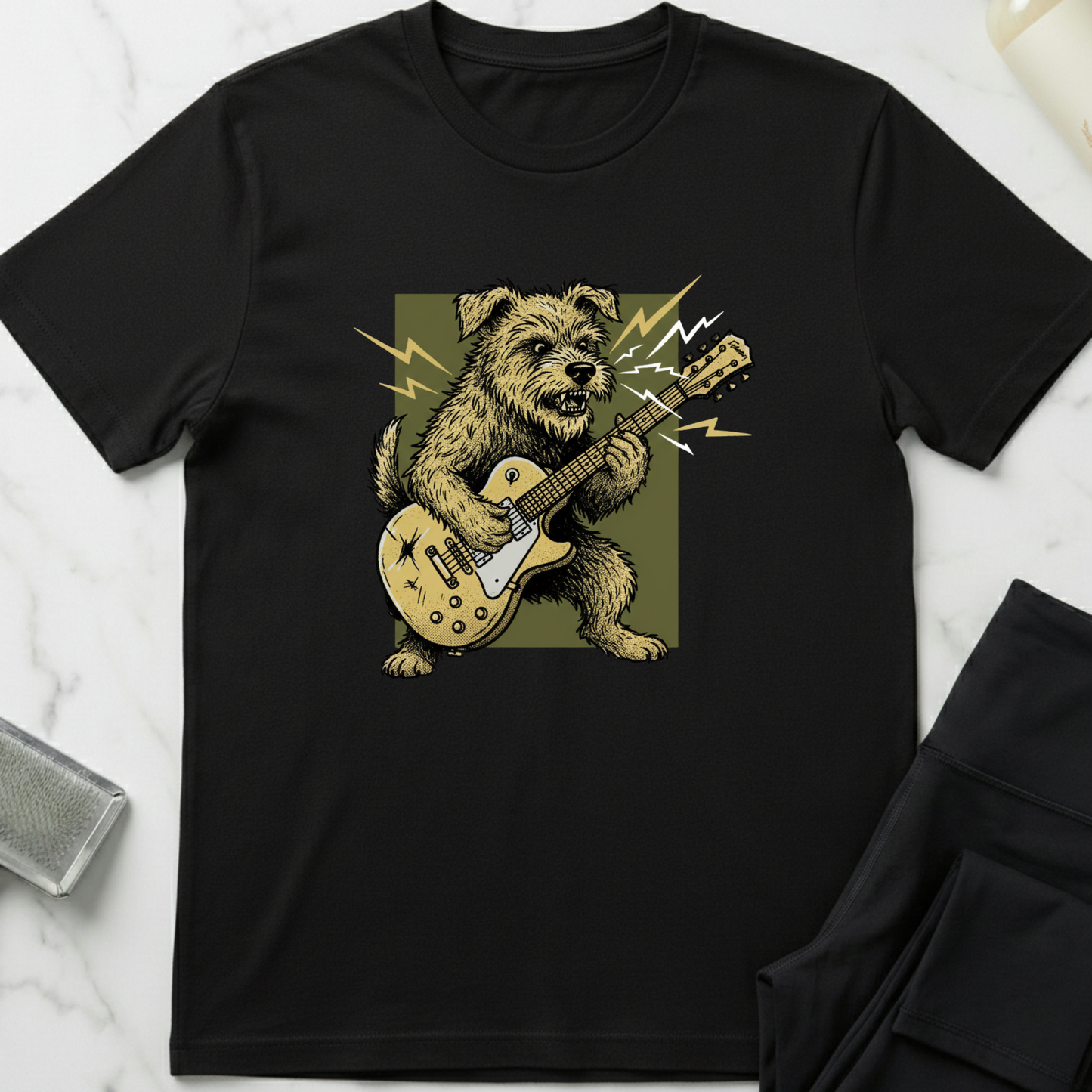 Black t-shirt with a dog playing guitar graphic on a white marble surface. Minimalist dog apparel by pemuyo.