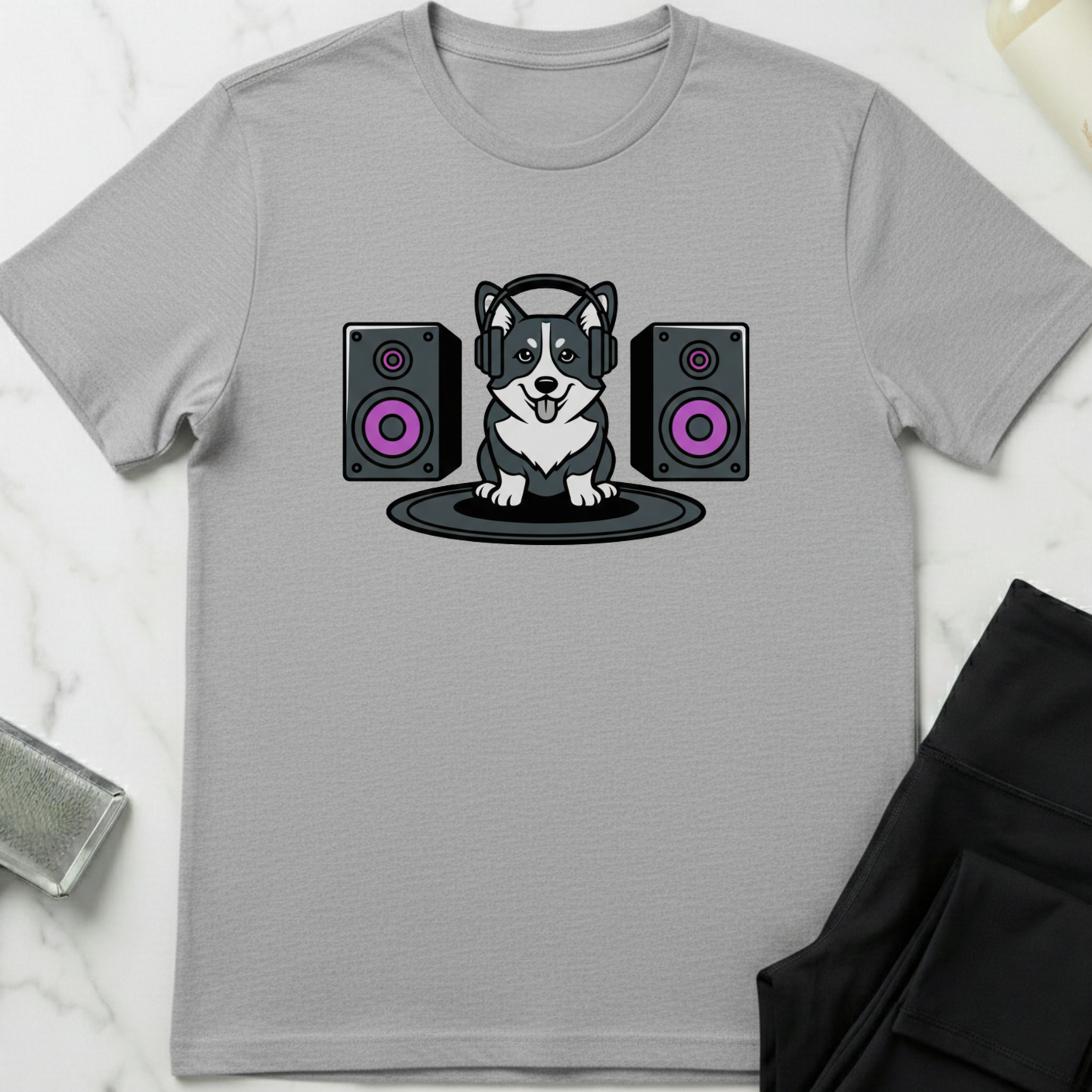 Gray t-shirt with a dog wearing headphones and speakers design on a white marble surface. Minimalist dog apparel by pemuyo.