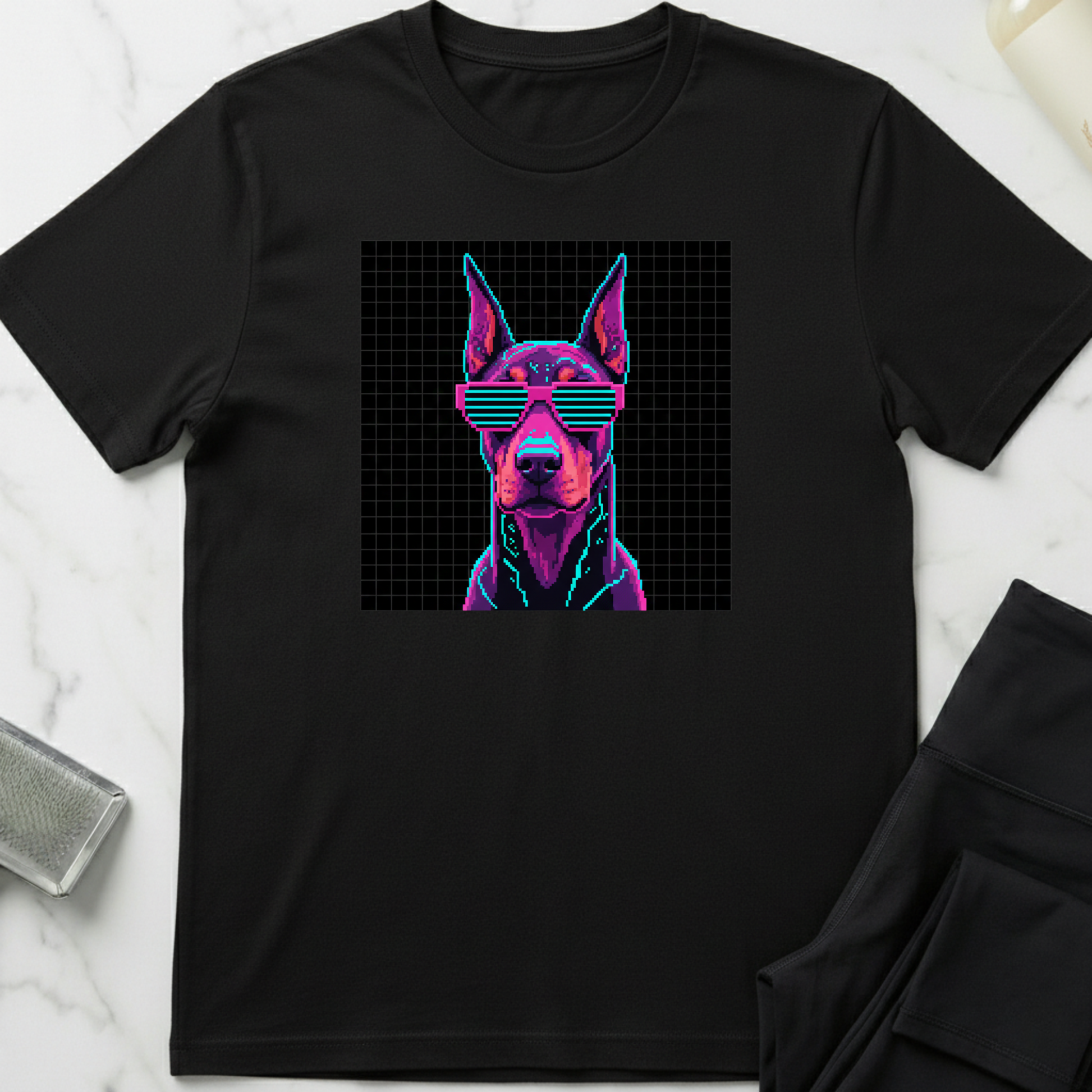 Black t-shirt with a dog graphic wearing sunglasses on a white marble surface. Minimalist dog apparel by pemuyo.