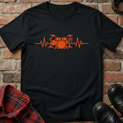 Black t-shirt with orange drum set design on a brick wall background. Minimalist music apparel by pemuyo.