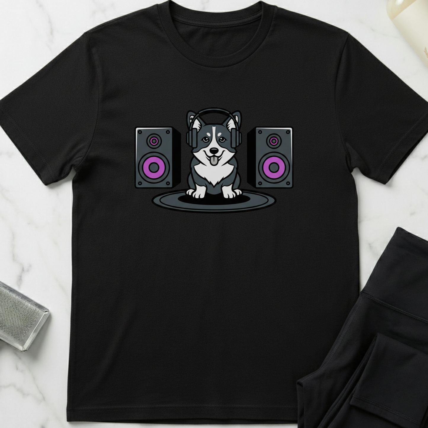 Black t-shirt with a dog wearing headphones and speakers design on a marble surface. Minimalist dog apparel by pemuyo.