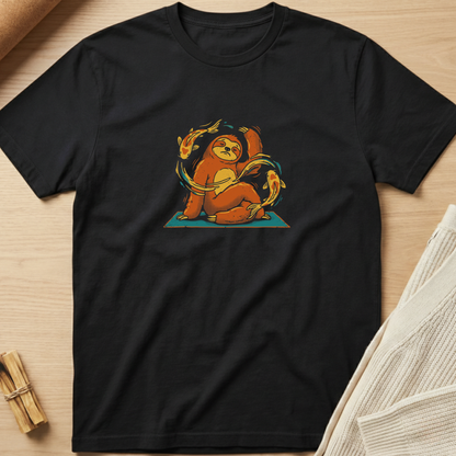 A black short-sleeve crewneck t-shirt laid flat on a light wood surface, featuring a colorful graphic of a sloth meditating on a teal mat with orange and yellow accents. Minimalist yoga apparel by pemuyo.