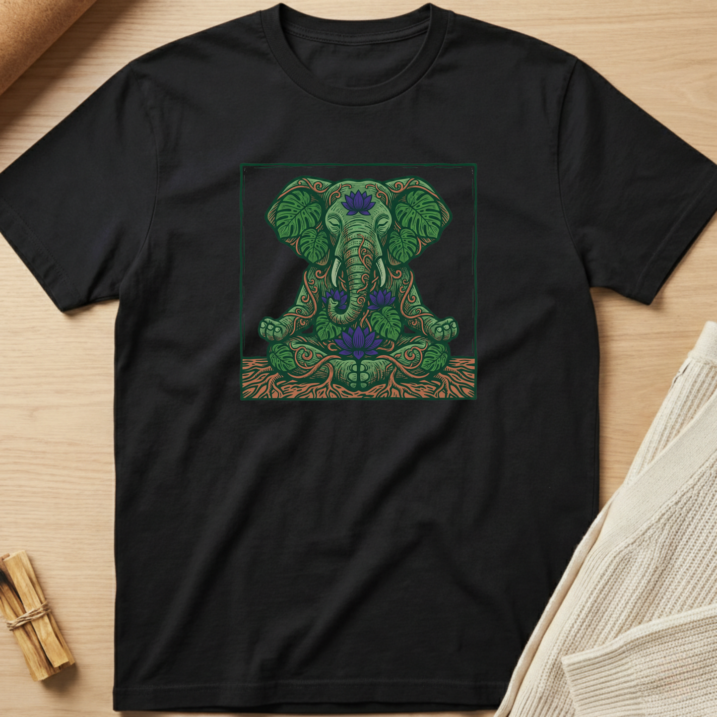 Black t-shirt with a green elephant design on a wooden surface. Minimalist yoga apparel by pemuyo.
