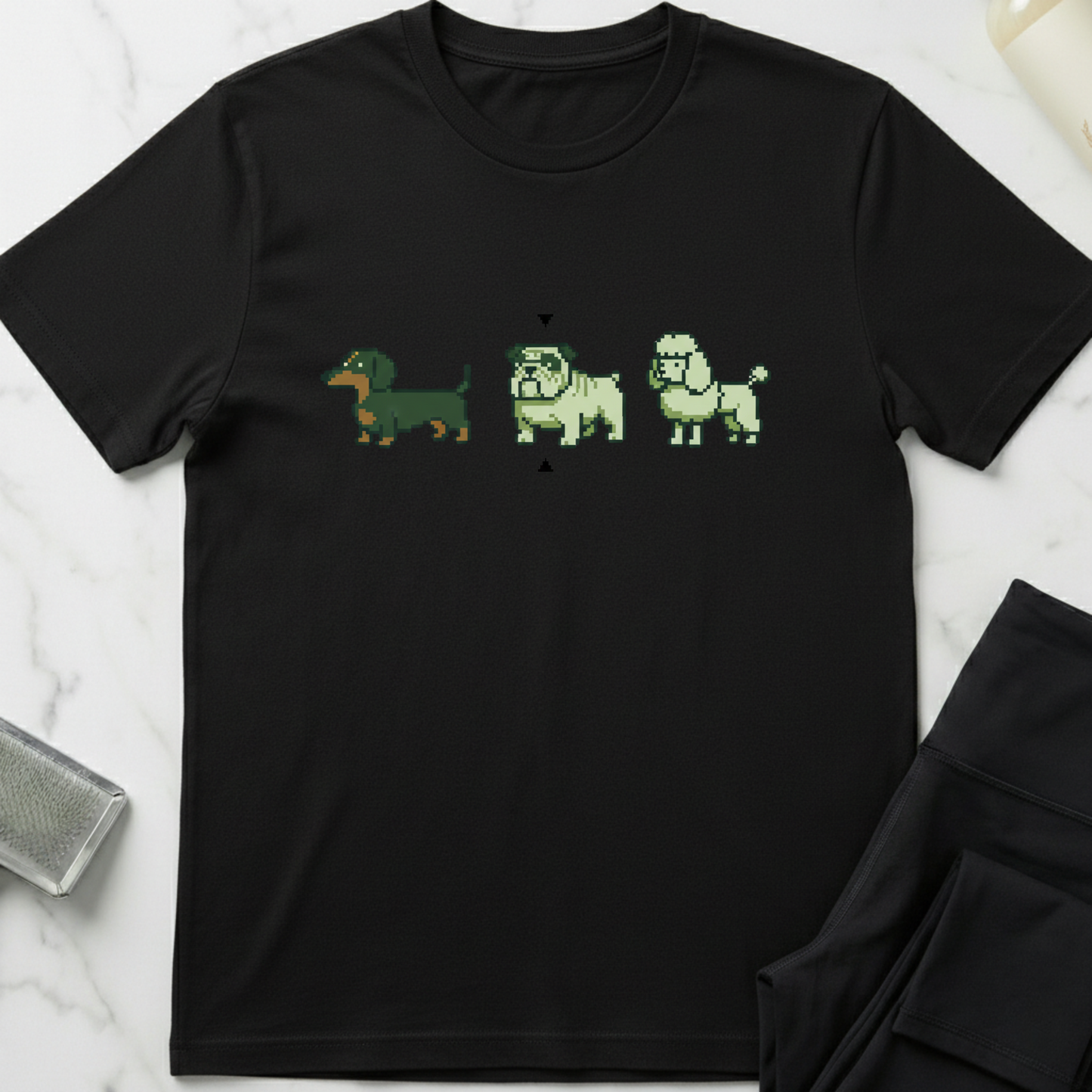 Black t-shirt with pixelated dog illustrations on a white marble surface. Minimalist dog apparel by pemuyo.