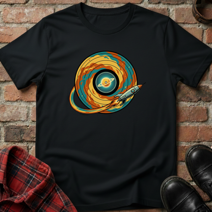 Black t-shirt with a colorful graphic design of a planet and spaceship, placed against a brick wall. Minimalist music apparel by pemuyo.