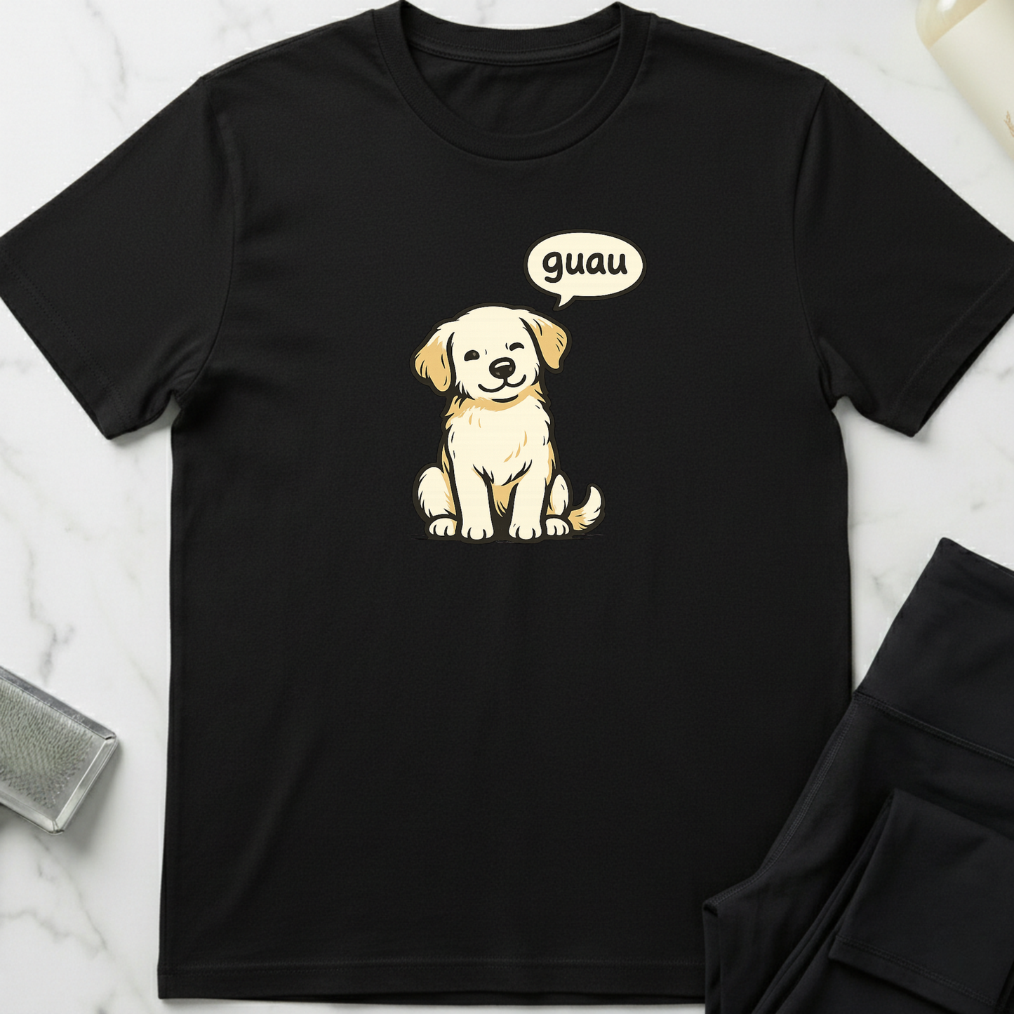 Black t-shirt with a cartoon dog and 'guau' speech bubble on a white marble surface. Minimalist dog apparel by pemuyo.