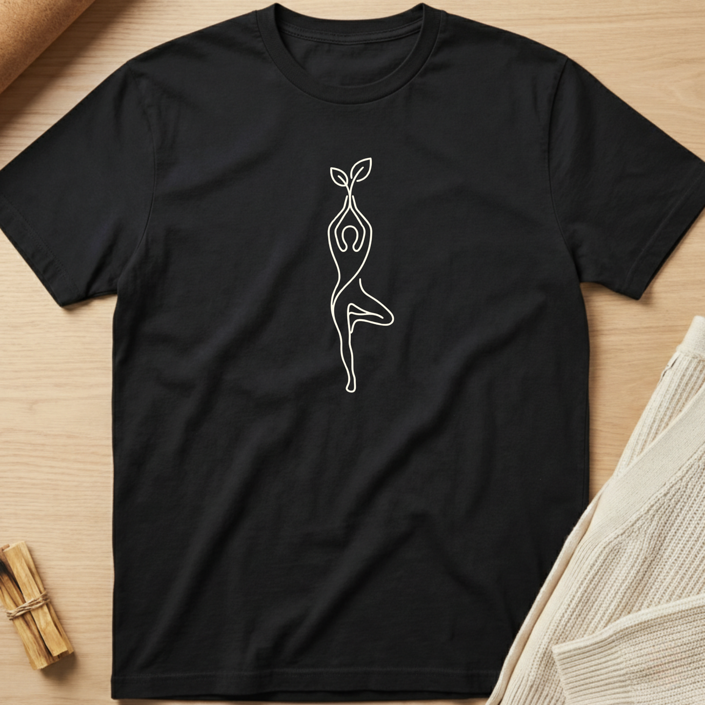 Black t-shirt with a white line drawing on a wooden surface. Minimalist yoga apparel by pemuyo.
