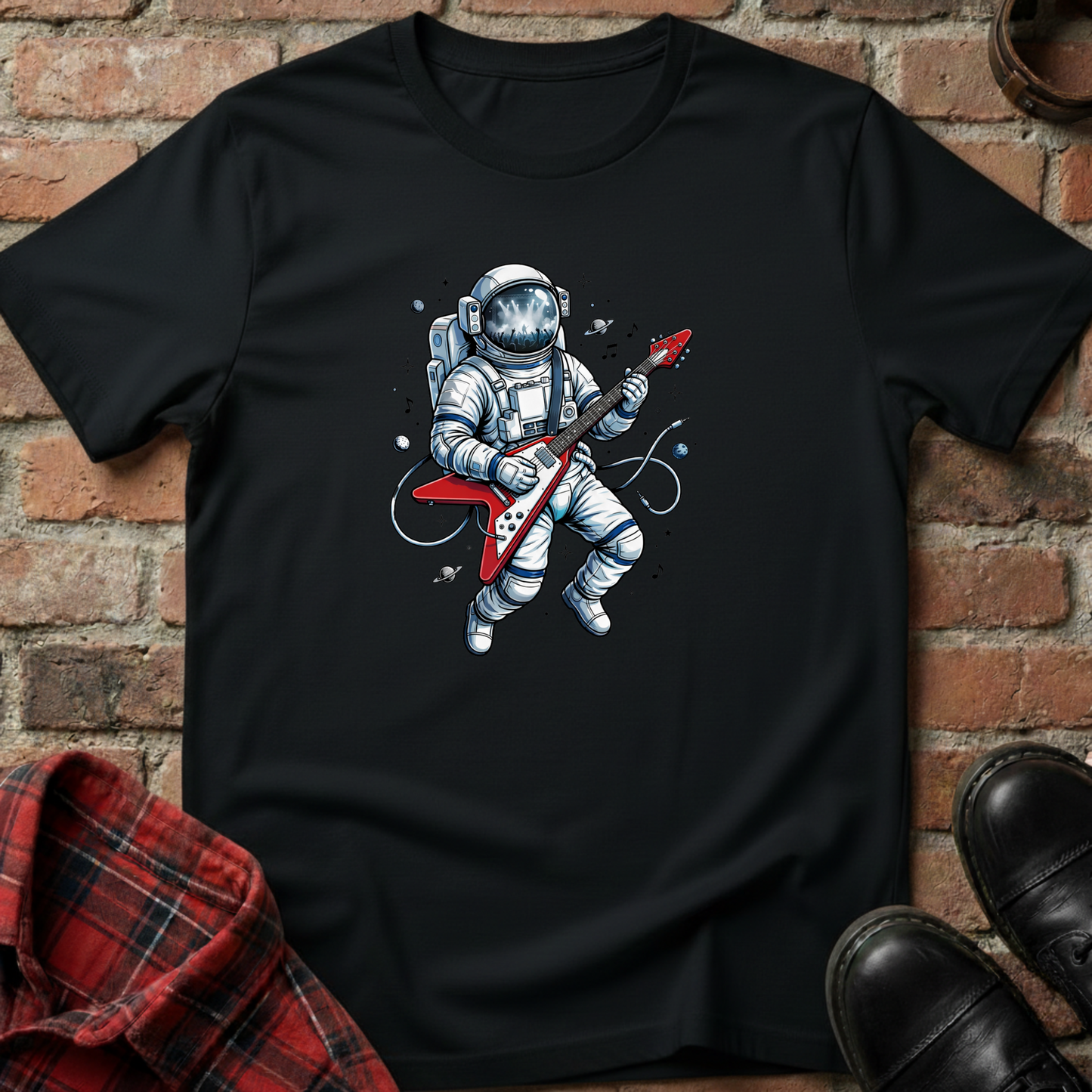 Black t-shirt with an astronaut playing a guitar graphic on a brick wall background. Minimalist music apparel by pemuyo.