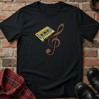 Black t-shirt with a cassette tape and music note design against a brick wall. Minimalist music apparel by pemuyo.