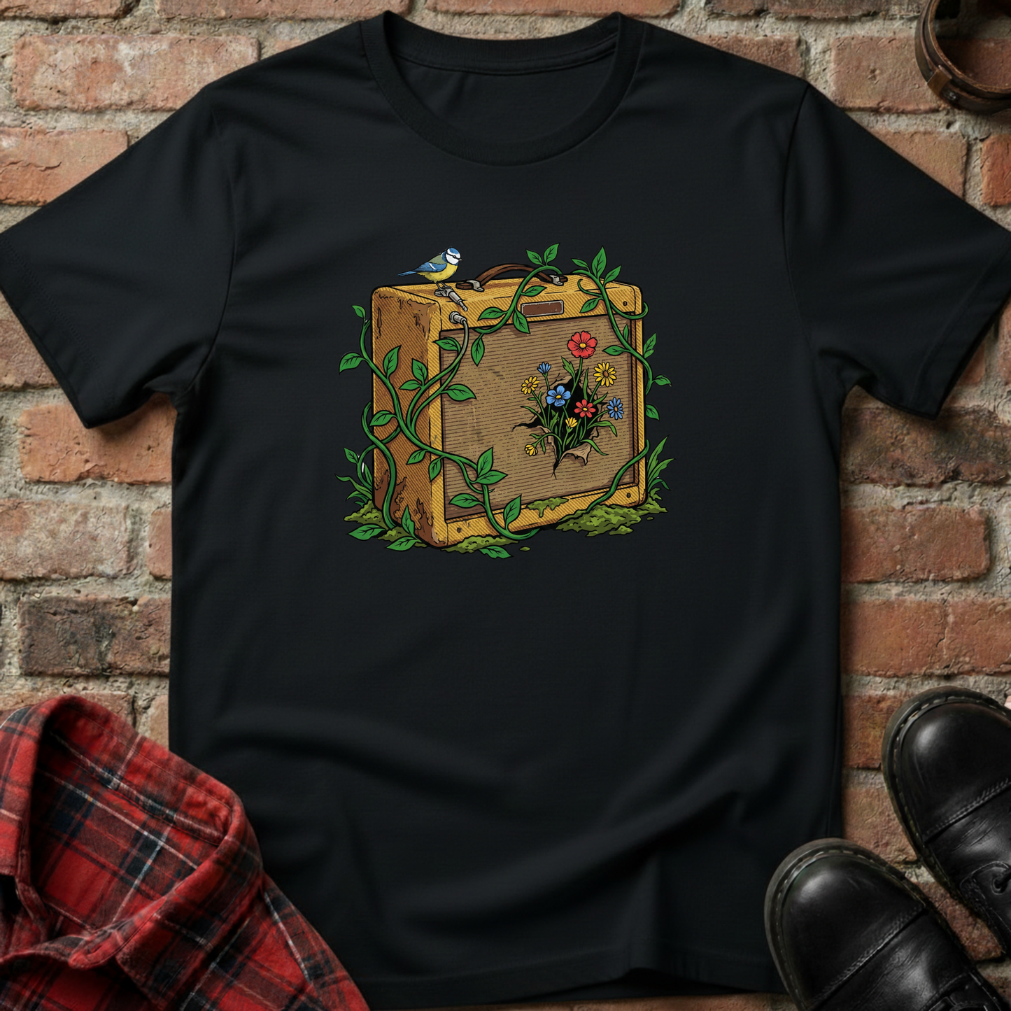 Black t-shirt with a suitcase and floral design on a brick wall background. Minimalist music apparel by pemuyo.