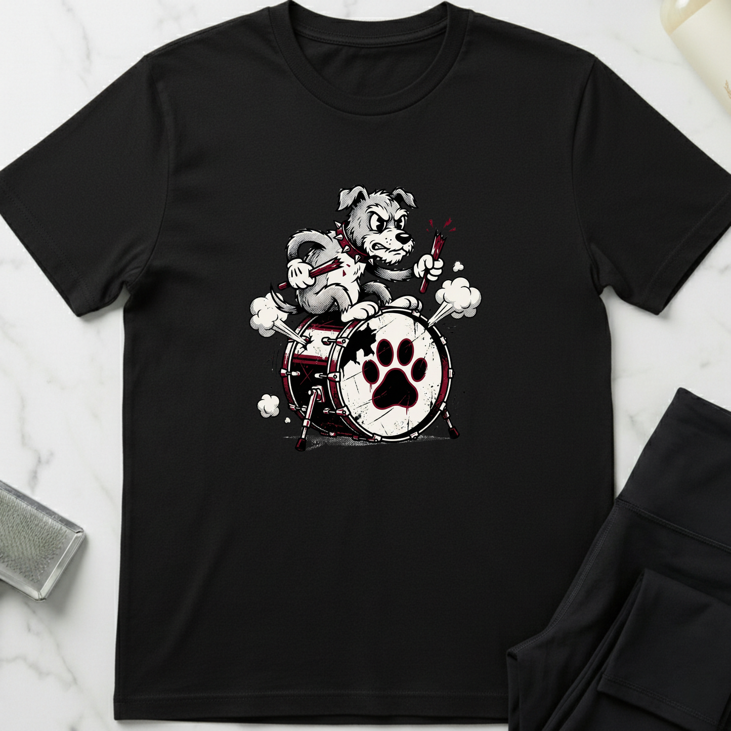 Black t-shirt with a graphic of a dog playing drums on a white marble surface. Minimalist dog apparel by pemuyo.