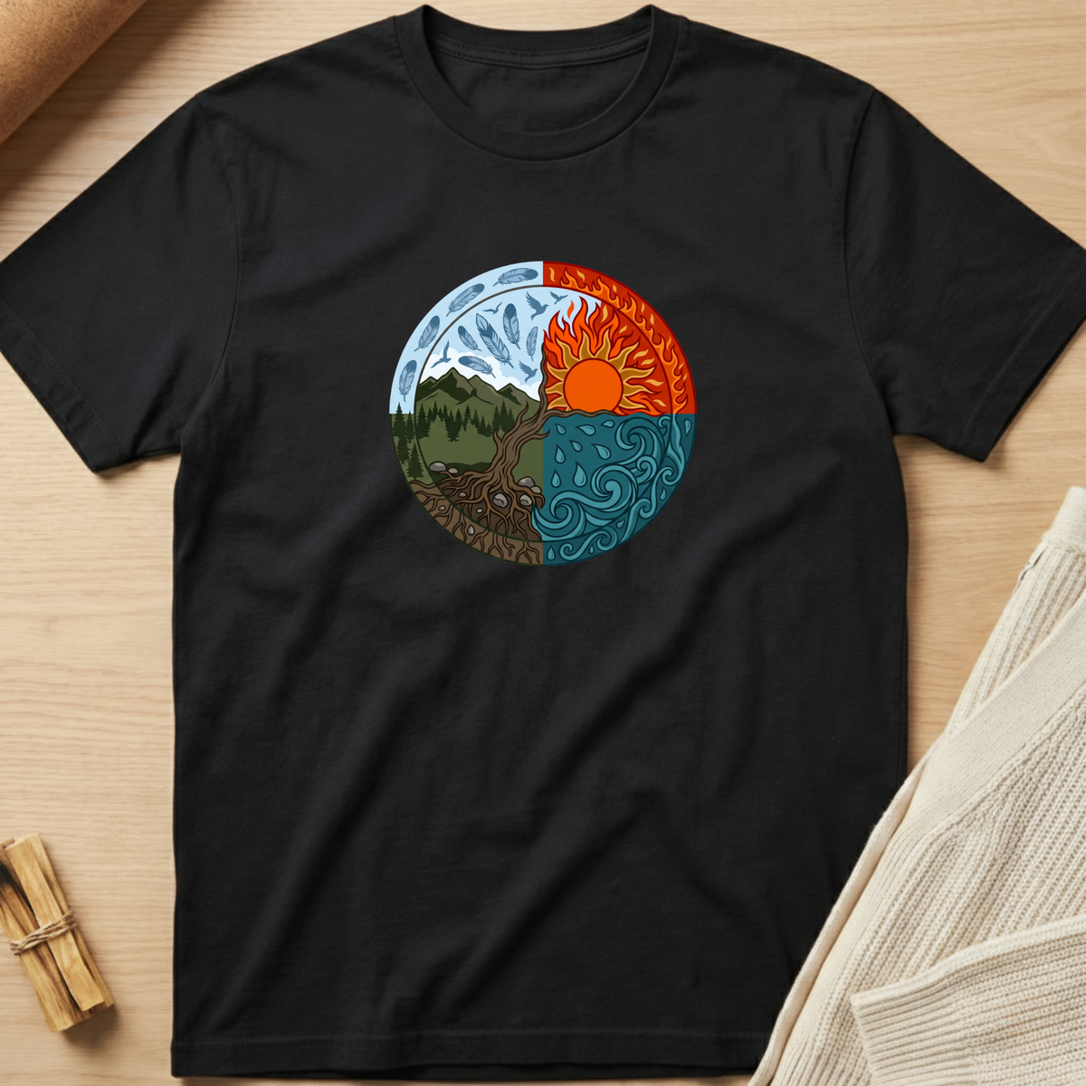 A black short-sleeve t-shirt laid flat on a light wood surface, featuring a circular yin-yang style graphic on the chest with a mountain and forest on one side and a sun over water on the other. Minimalist yoga apparel by pemuyo.