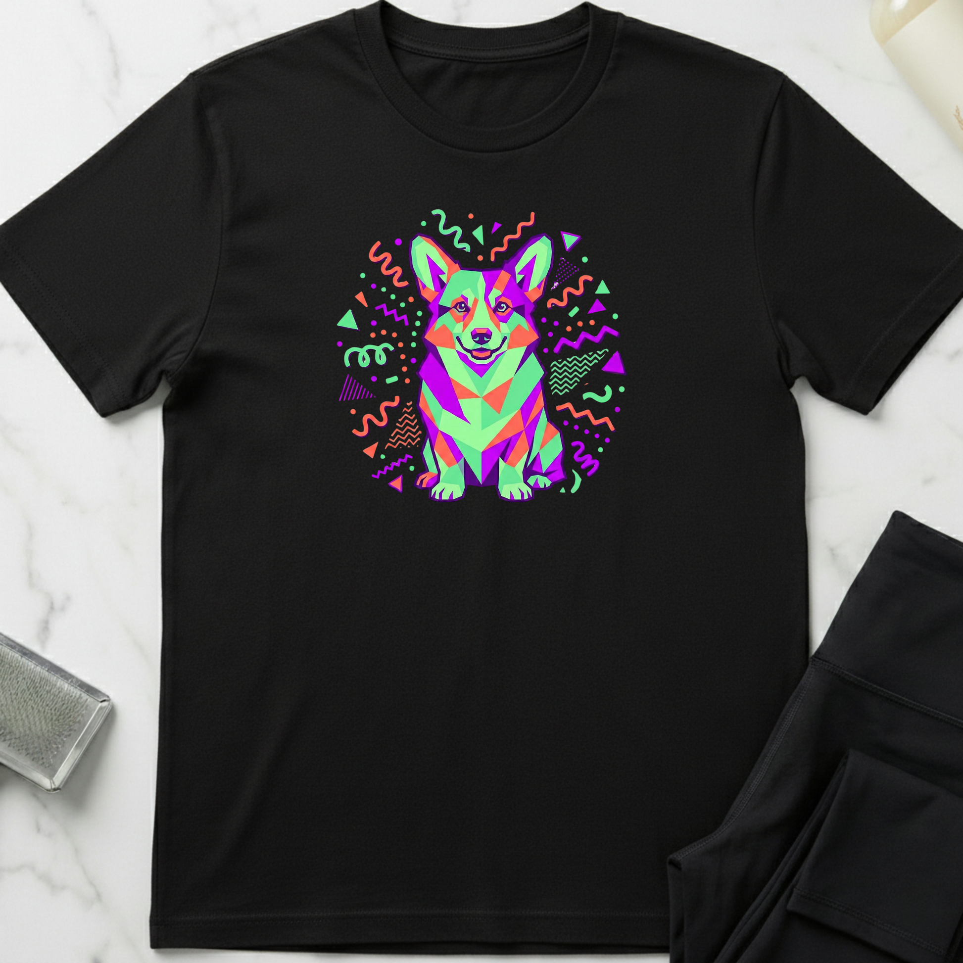 Black t-shirt with a colorful corgi graphic on a white marble surface. Minimalist dog apparel by pemuyo.