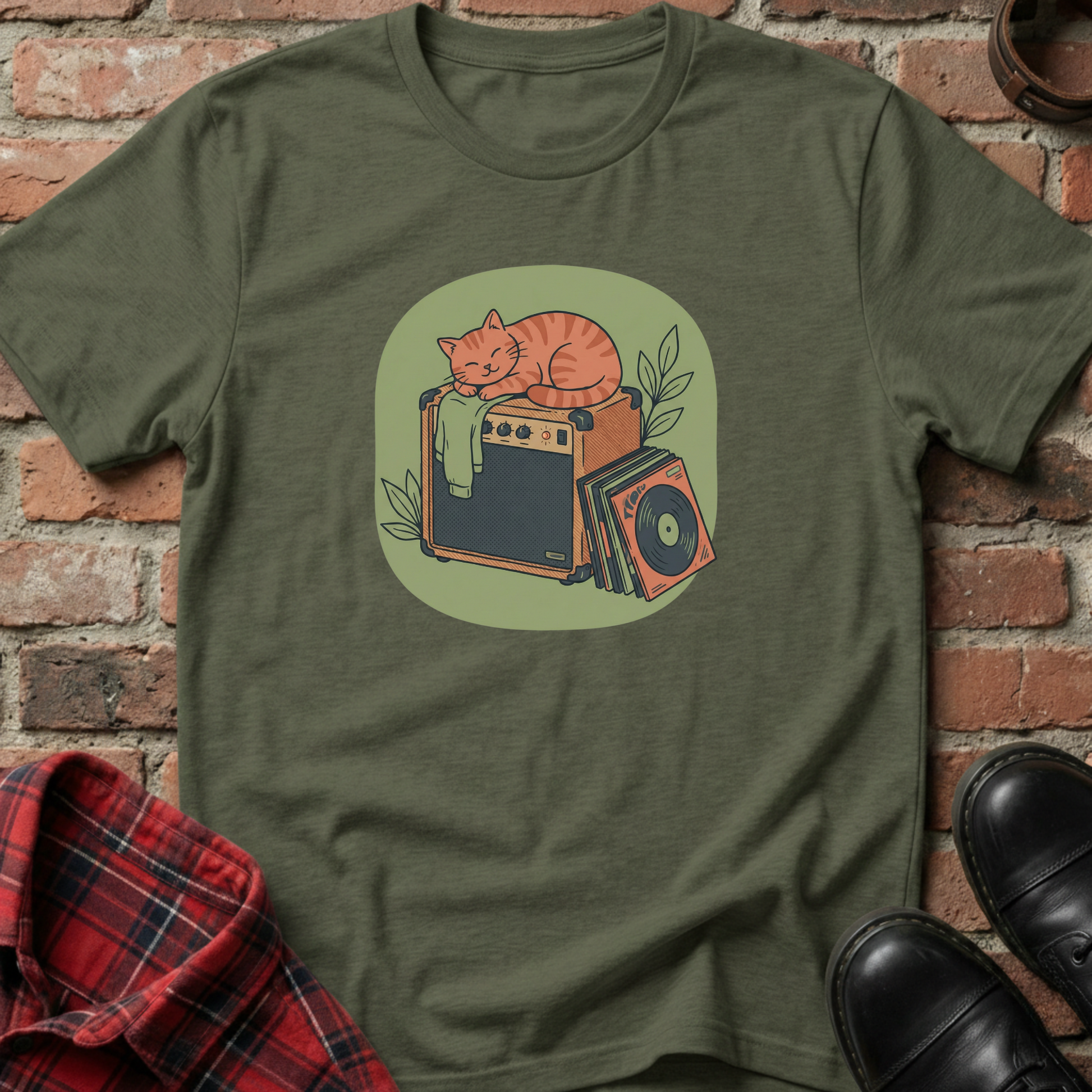 Green t-shirt with a graphic of a cat on an amplifier against a brick wall. Minimalist music apparel by pemuyo.