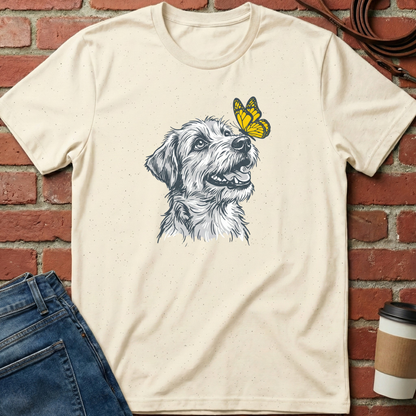 Beige t-shirt with a dog and butterfly graphic on a brick wall background. Minimalist dog apparel by pemuyo.