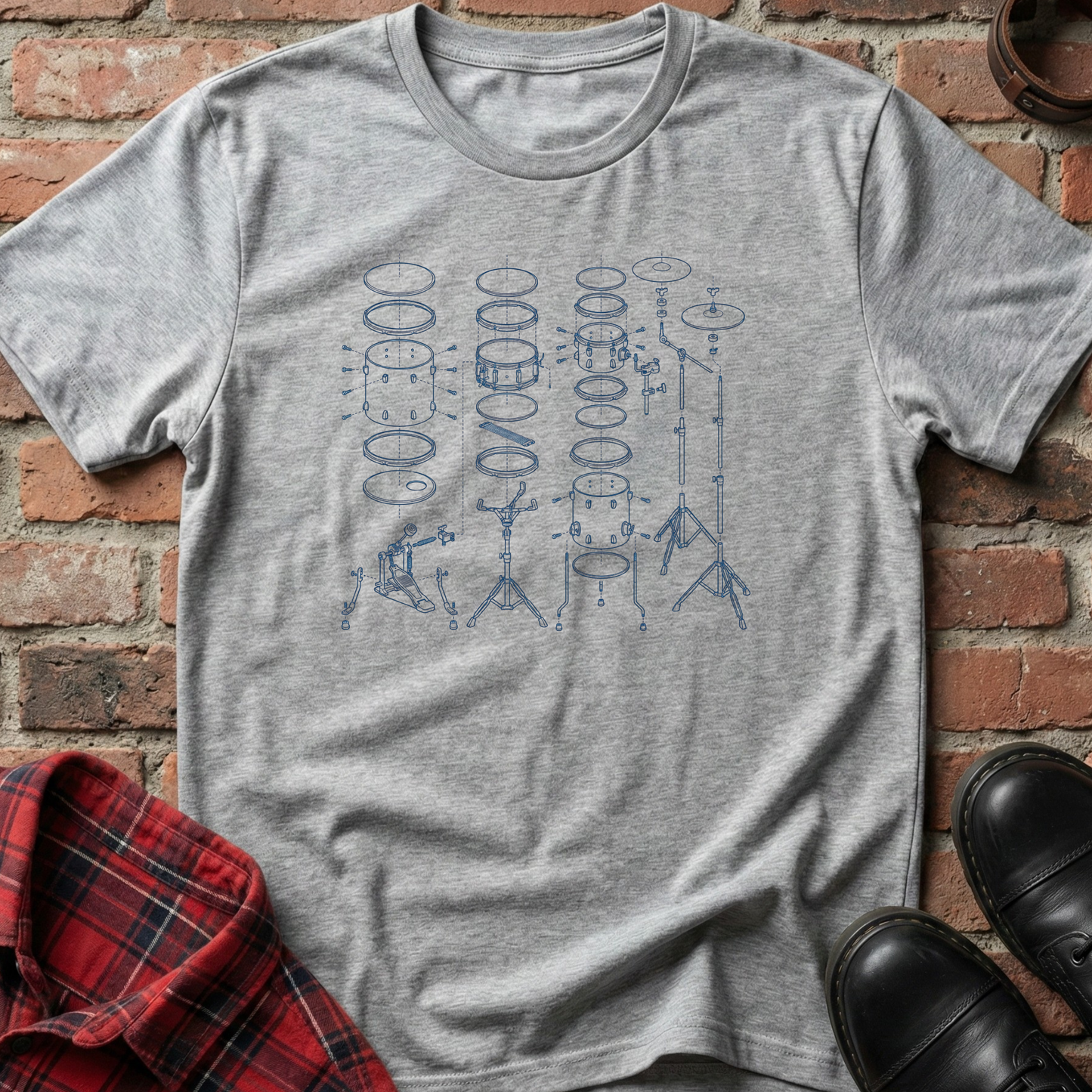 Gray t-shirt with blue drum set design on a brick surface. Minimalist music apparel by pemuyo.
