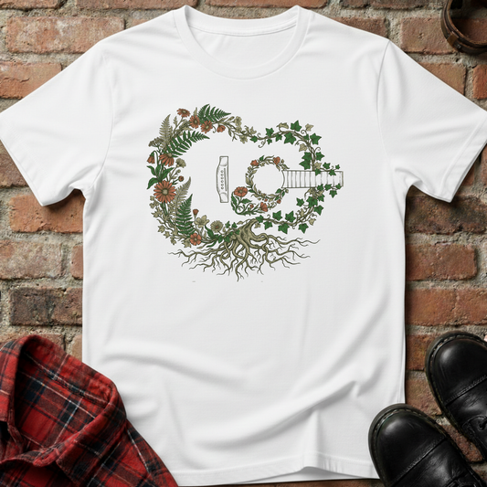 White t-shirt with a guitar and floral design on a brick surface. Minimalist music apparel by pemuyo.