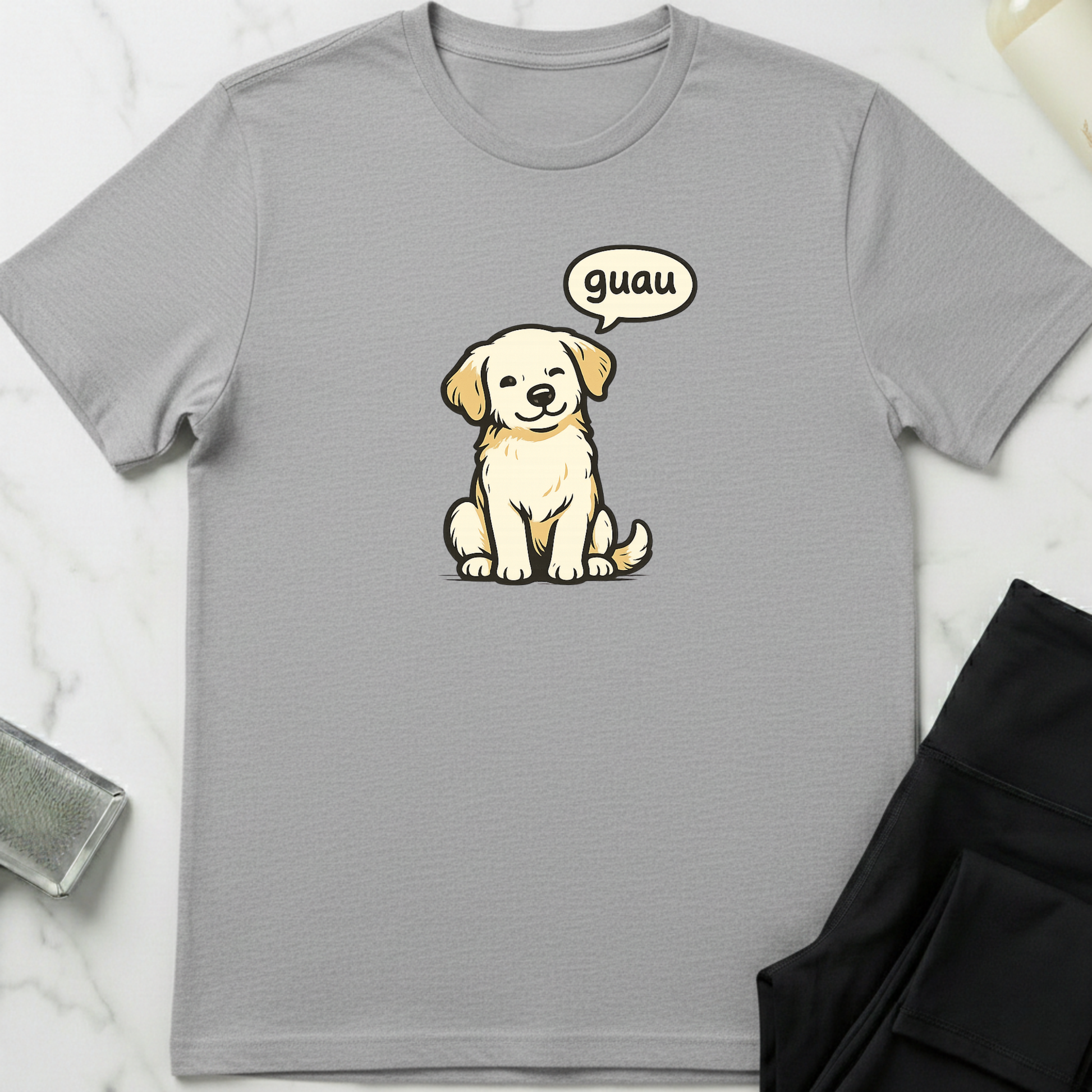 Gray t-shirt with a cartoon dog and speech bubble on a marble surface. Minimalist dog apparel by pemuyo.