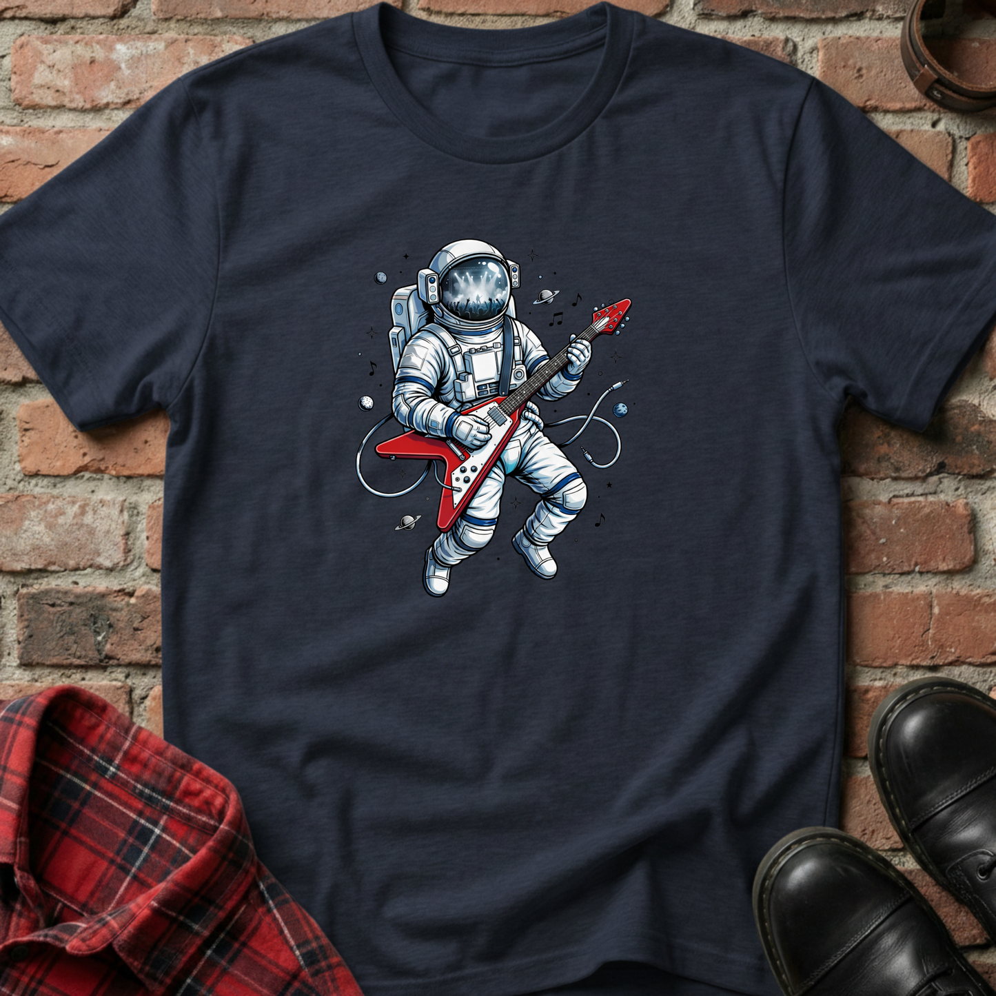 Navy blue t-shirt with an astronaut playing a guitar graphic on a brick background. Minimalist music apparel by pemuyo.