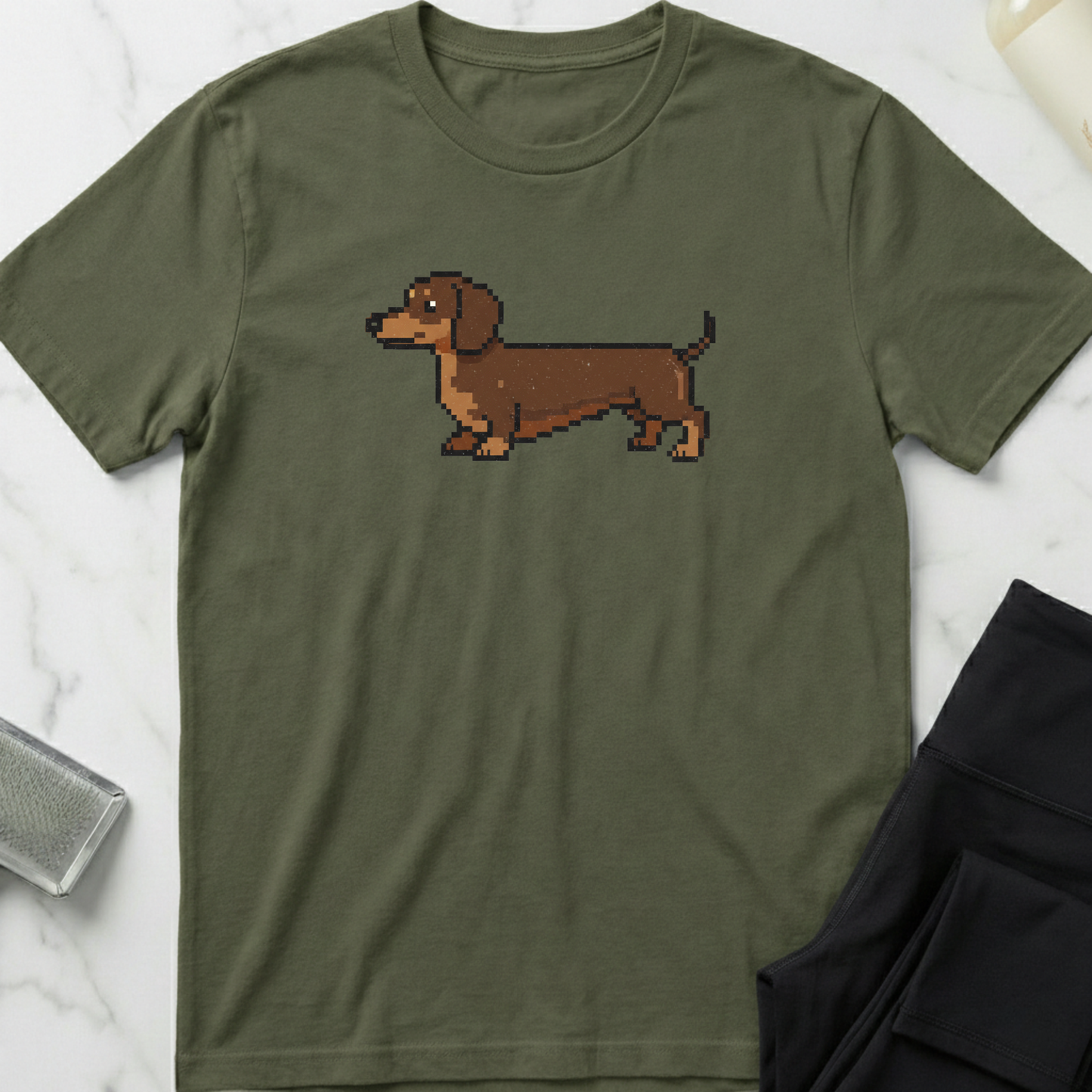 Green t-shirt with a pixelated dachshund graphic on a marble surface. Minimalist dog apparel by pemuyo.