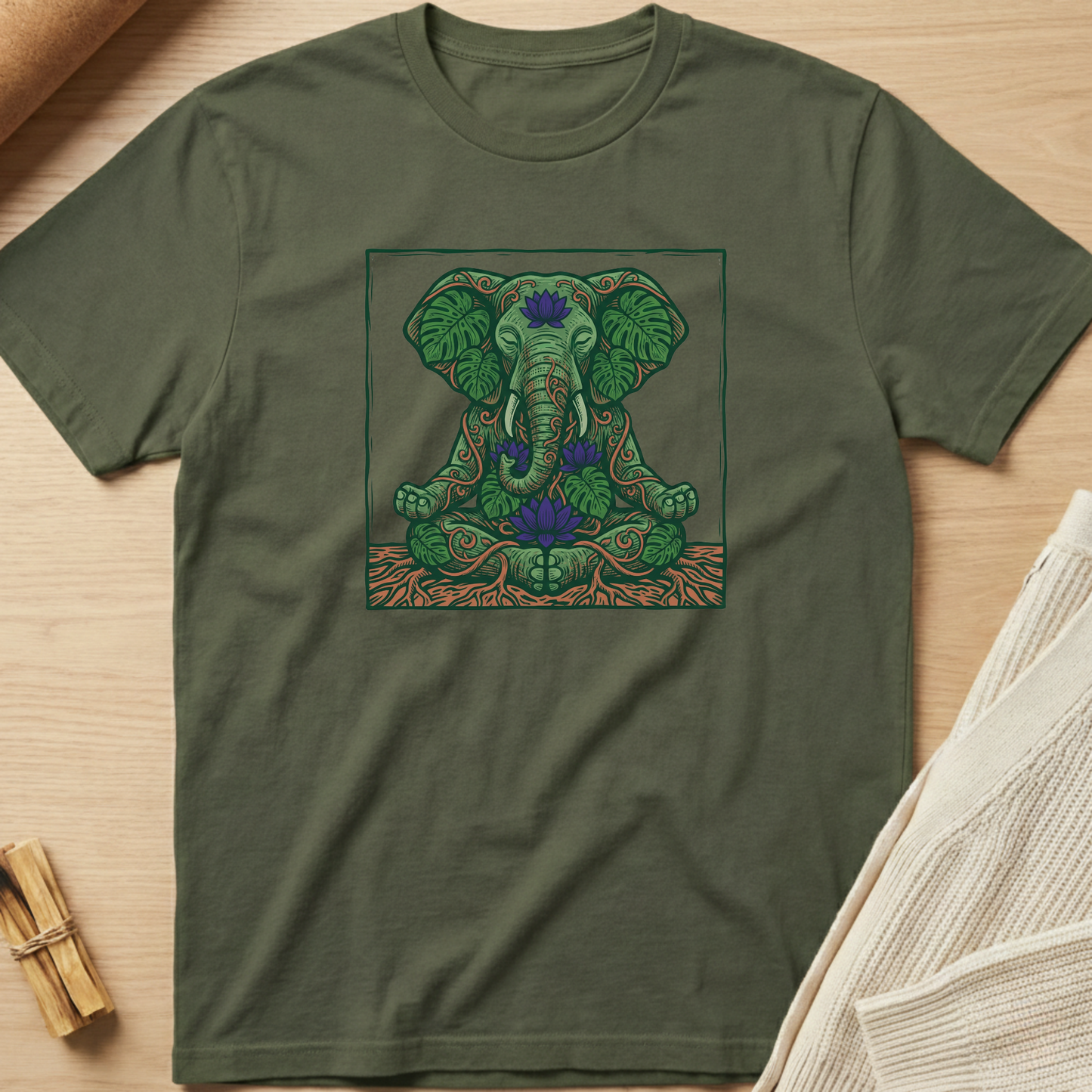 Green t-shirt with an elephant and lotus design on a wooden surface. Minimalist yoga apparel by pemuyo.