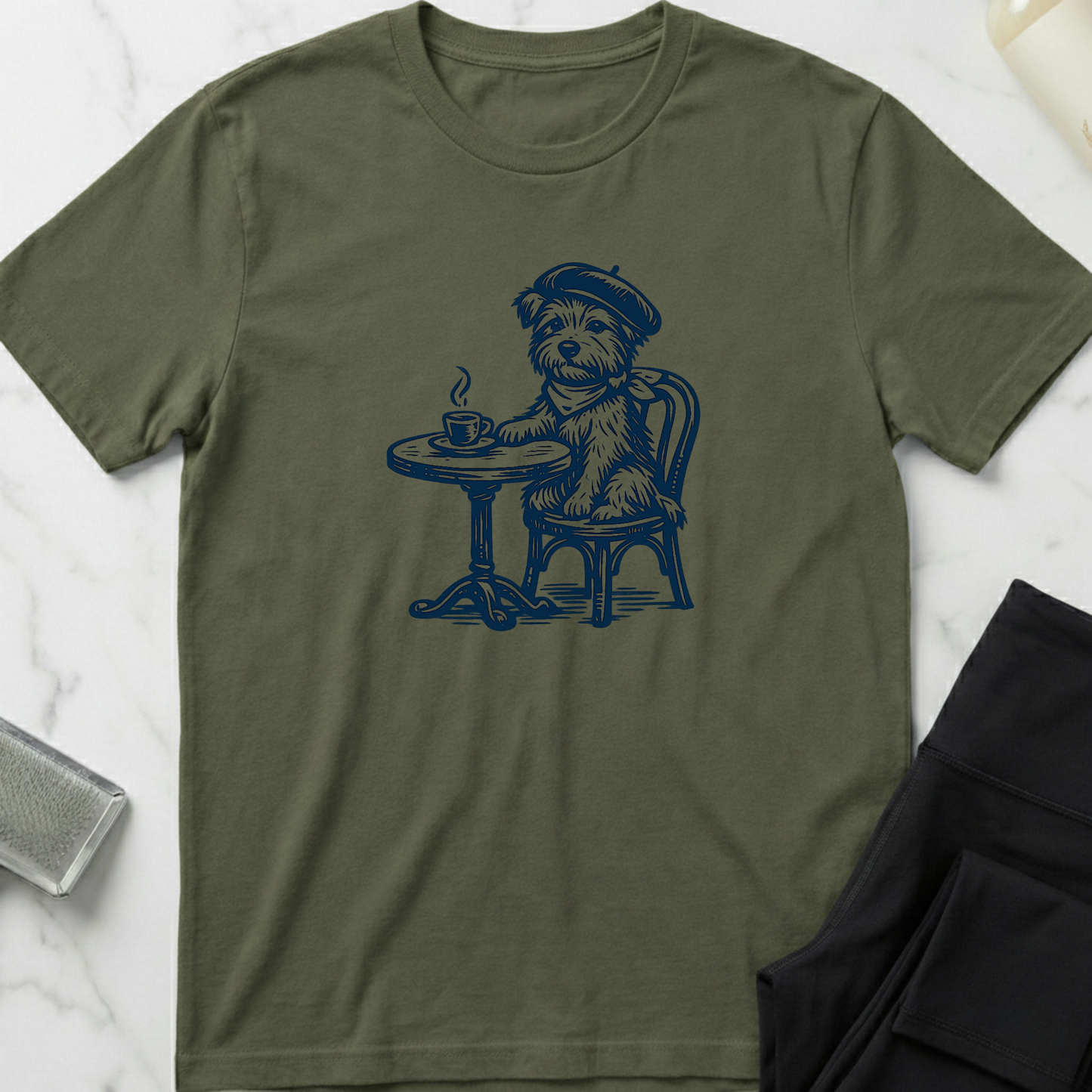 Green t-shirt with a dog graphic sitting at a table and drinking coffee on a white marble surface. Minimalist dog apparel by pemuyo.