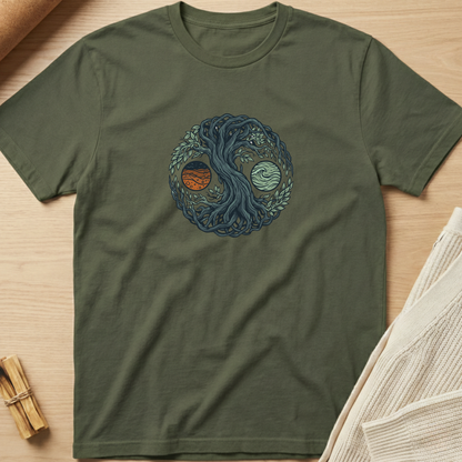 An olive green short-sleeve t-shirt with a central graphic of a yin-yang symbol formed by a tree and ocean waves, with one half showing a red sun and the other half showing a light blue moon. The shirt is laid flat on a light wood background with styled props. Minimalist yoga apparel by pemuyo.