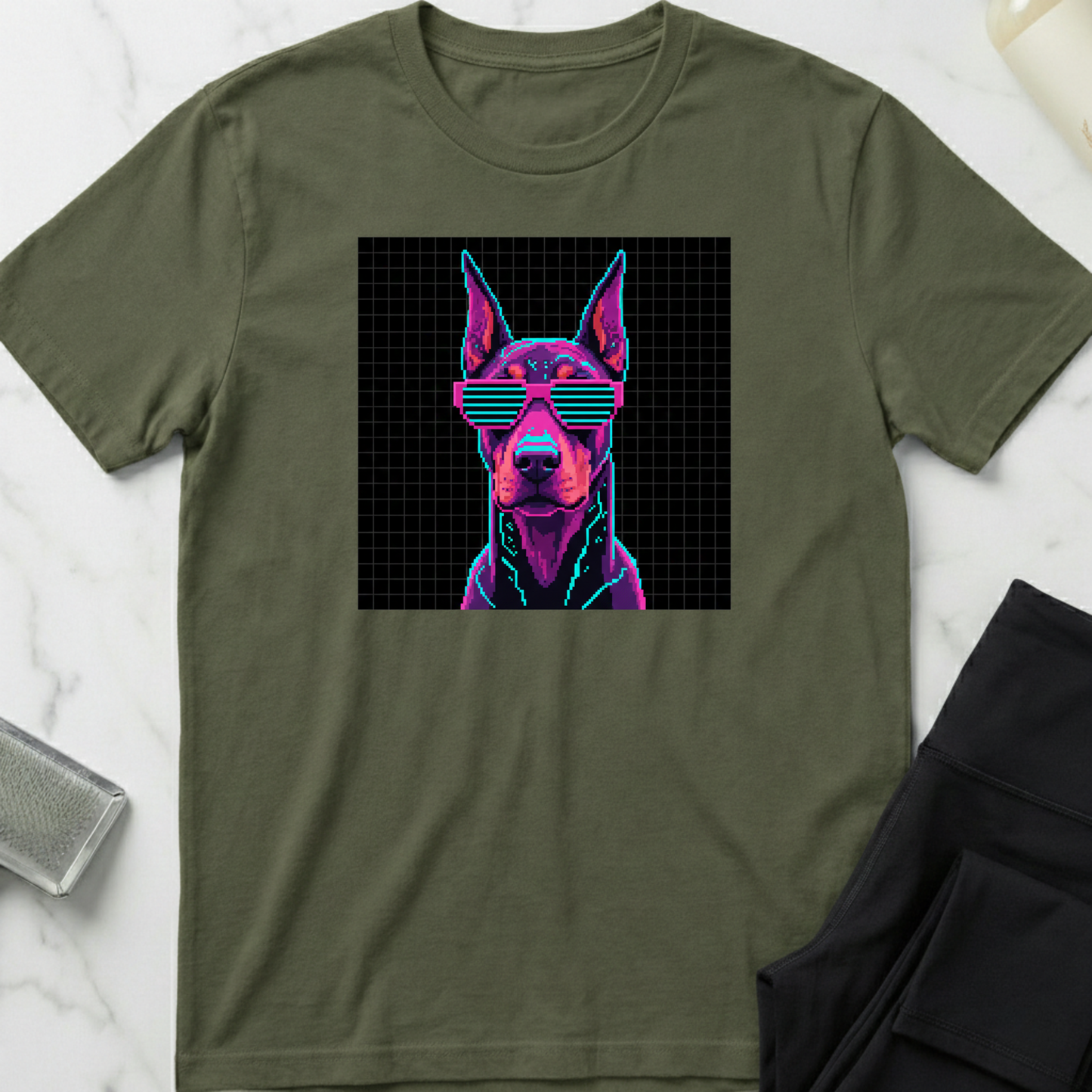 Green t-shirt with a dog wearing sunglasses graphic on a white marble surface. Minimalist dog apparel by pemuyo.