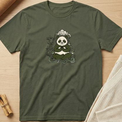 An olive green short-sleeve t-shirt with a graphic of a panda meditating on a bamboo stalk, laid flat on a light wood background with styled props. Minimalist yoga apparel by pemuyo.
