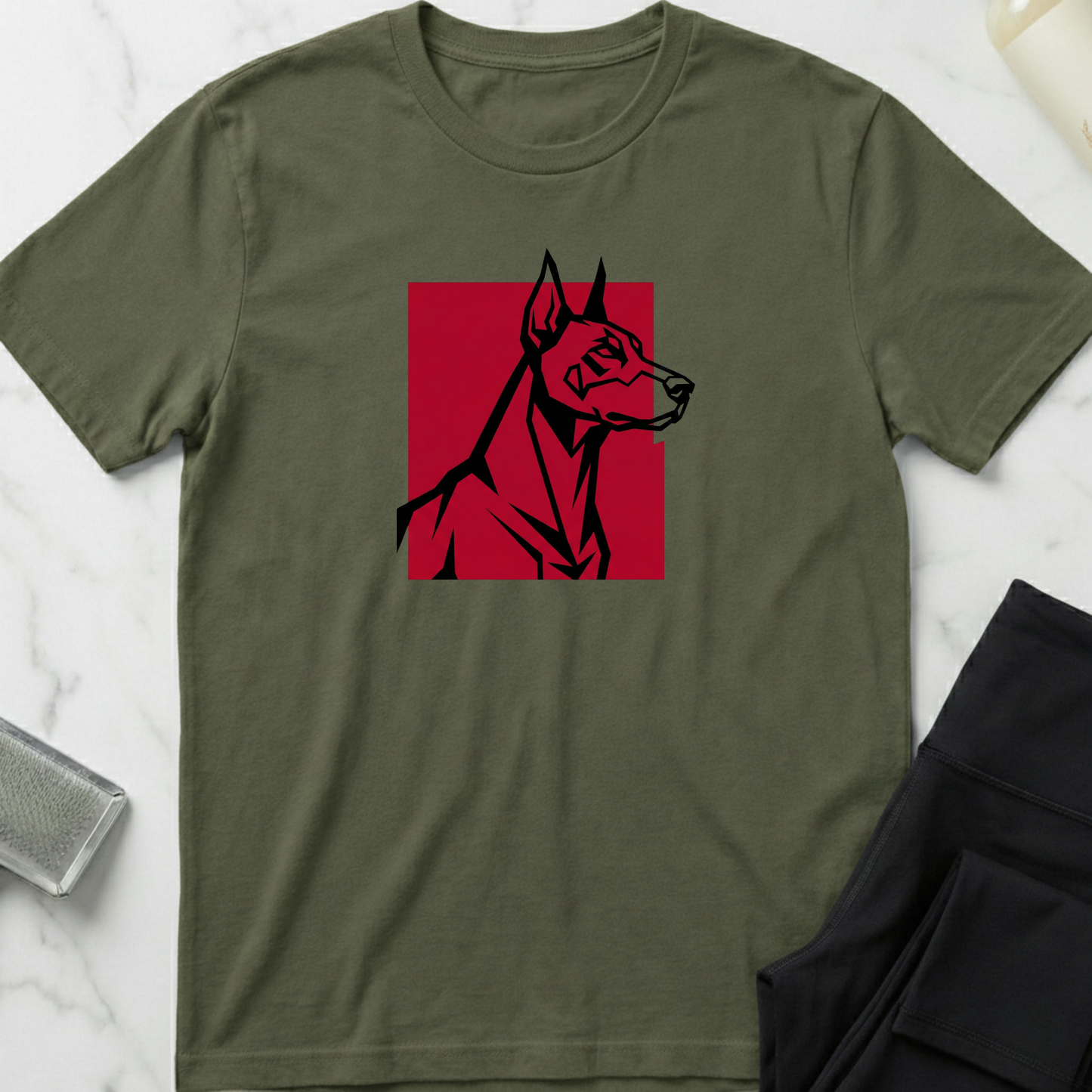 Green t-shirt with a red and black dog graphic on a white marble surface. Minimalist dog apparel by pemuyo.