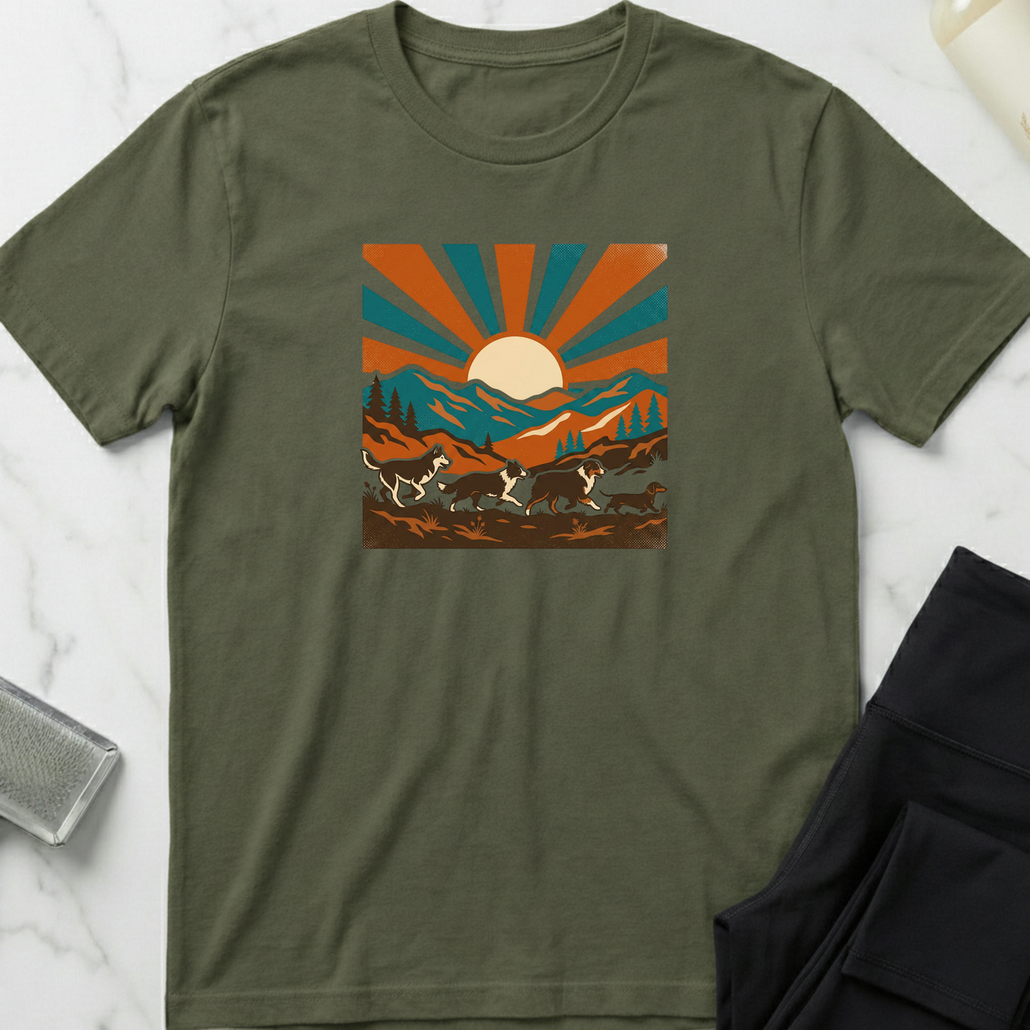 Green t-shirt with a mountain and sun graphic on a white marble surface. Minimalist dog apparel by pemuyo.