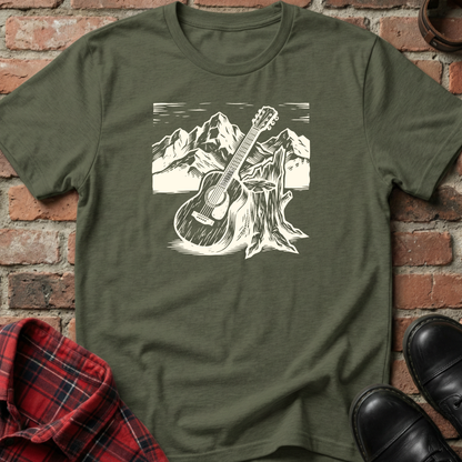 Green t-shirt with a guitar and mountain graphic on a brick background. Minimalist music apparel by pemuyo.
