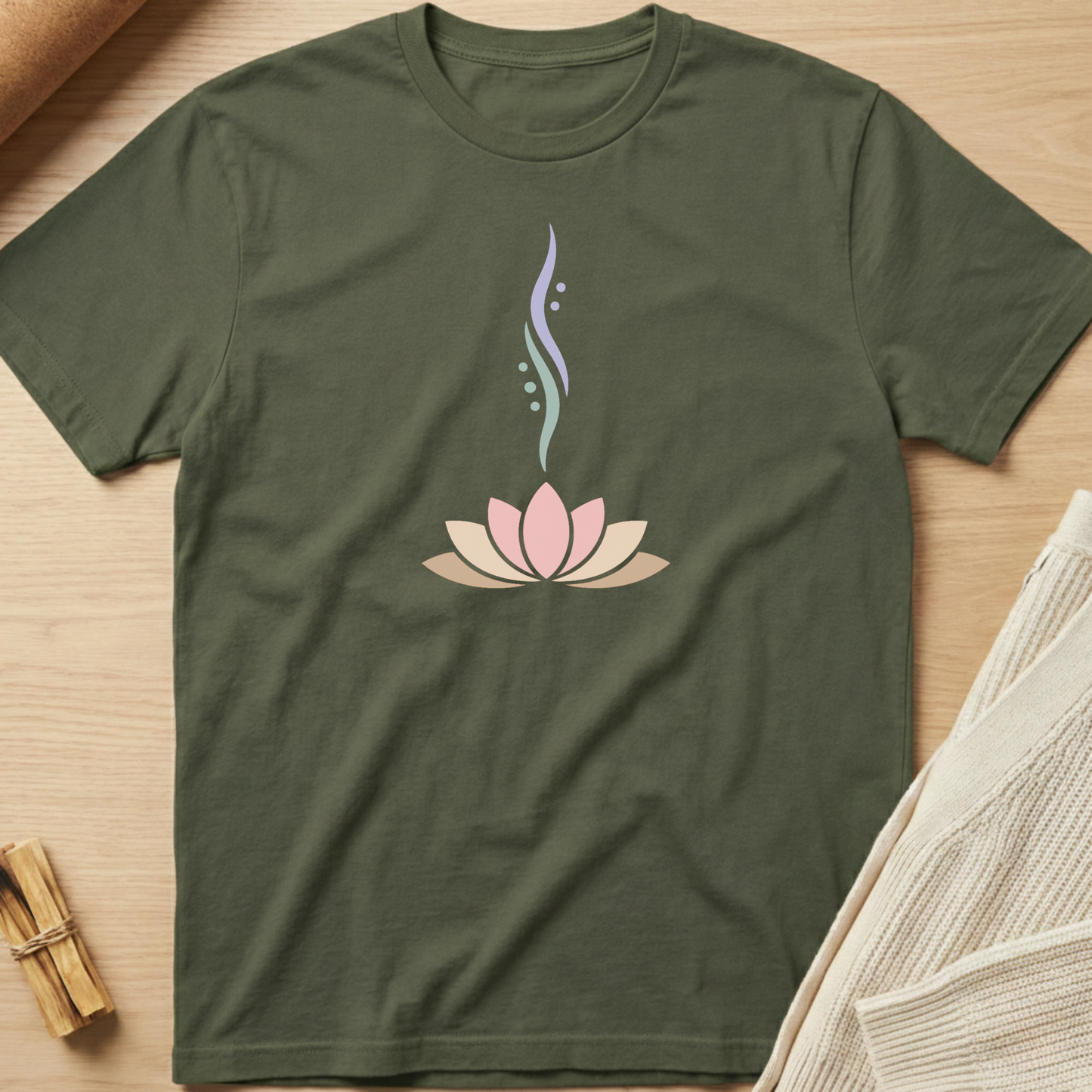 Green t-shirt with a pink lotus flower design on a wooden surface. Minimalist yoga apparel by pemuyo.