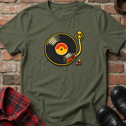 Green t-shirt with a vinyl record design on a brick wall background. Minimalist music apparel by pemuyo.