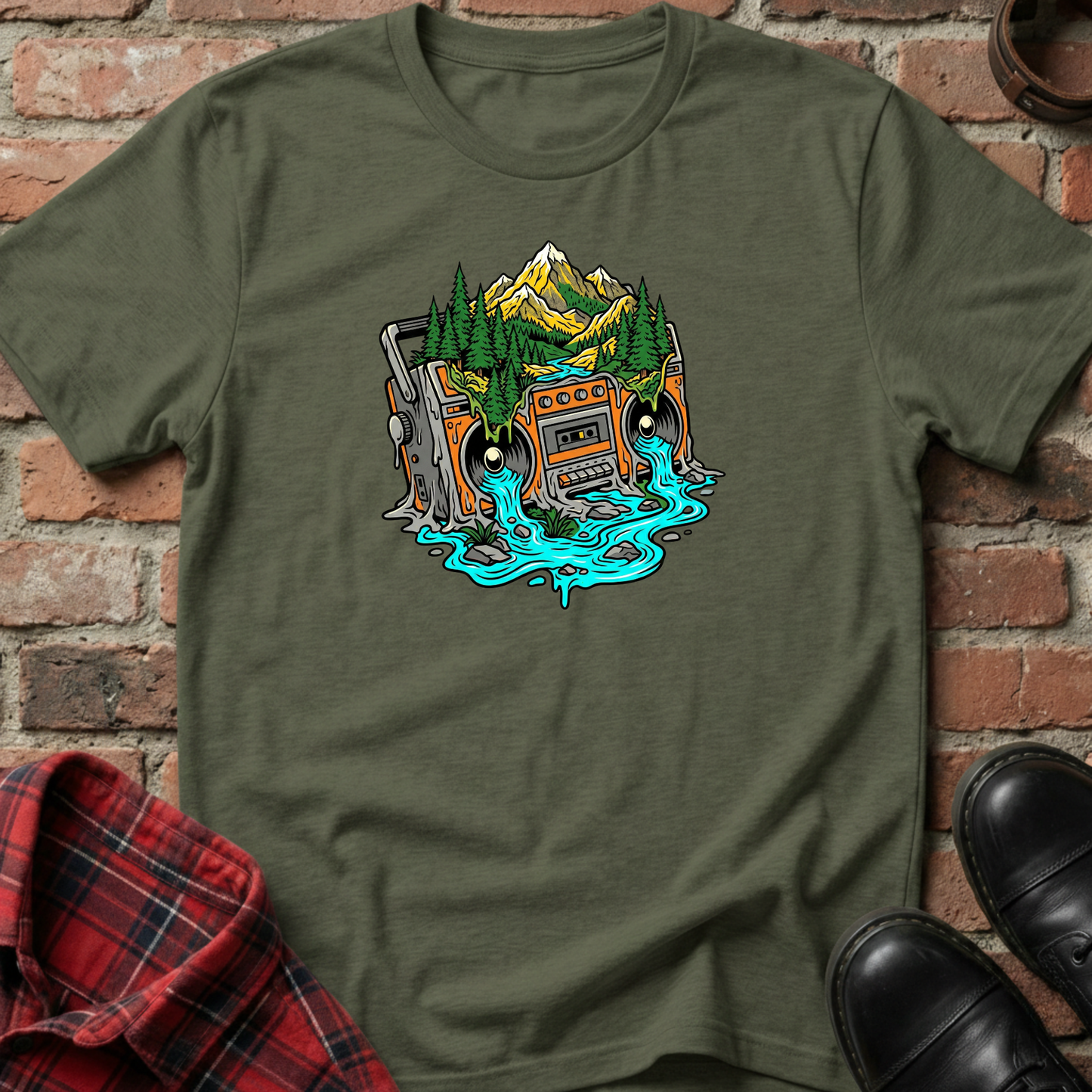 Green t-shirt with a graphic design of a cassette tape and mountains on a brick background. Minimalist music apparel by pemuyo.