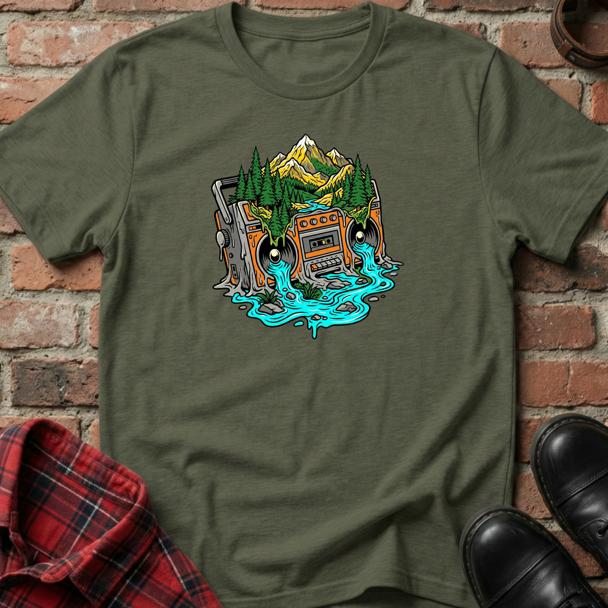 Green t-shirt with a graphic design of a cassette tape and mountains on a brick background. Minimalist music apparel by pemuyo.