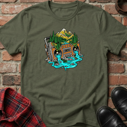Green t-shirt with a graphic design of a cassette tape and mountains on a brick background. Minimalist music apparel by pemuyo.