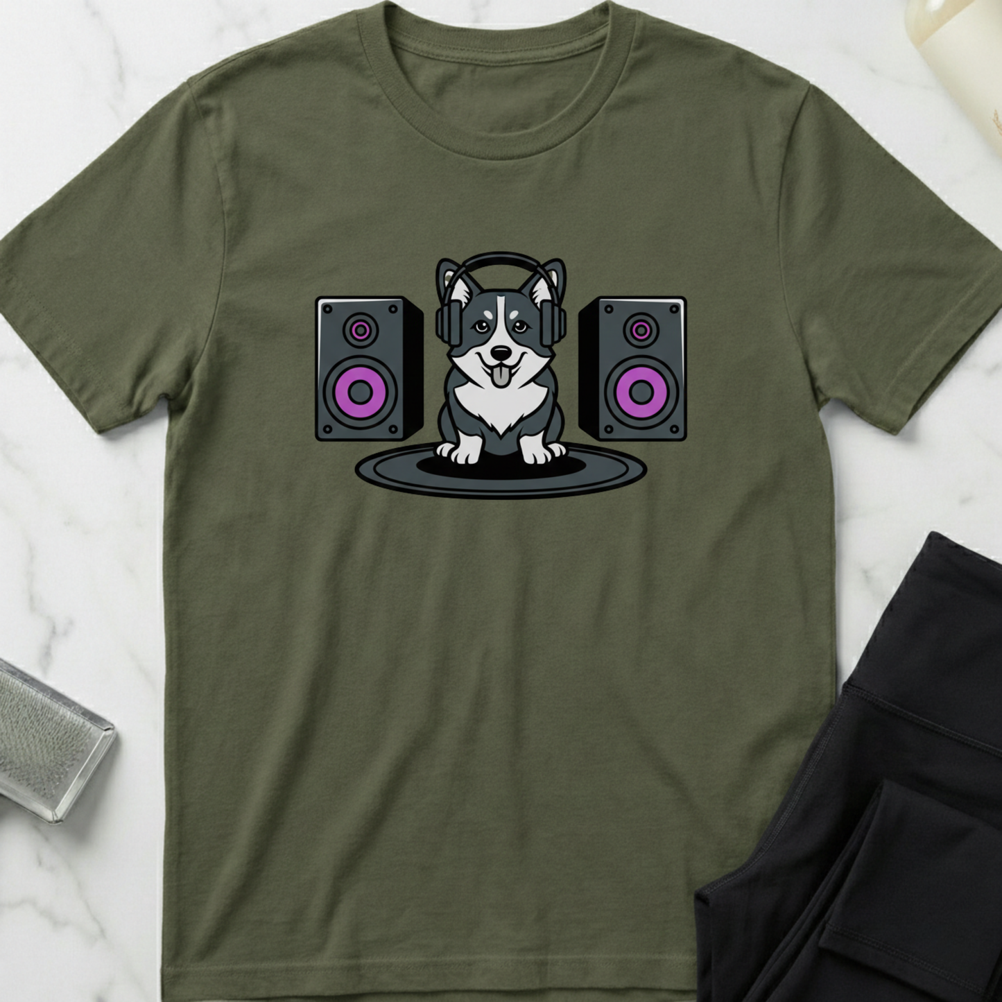 Green t-shirt with a dog wearing headphones and speakers design on a white marble surface. Minimalist dog apparel by pemuyo.