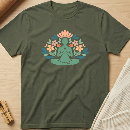 Green t-shirt with a meditating figure and floral design on a wooden surface. Minimalist yoga apparel by pemuyo.