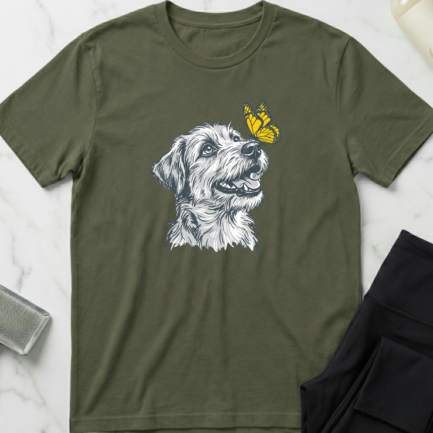 Green t-shirt with a dog graphic and yellow crown on a marble surface. Minimalist dog apparel by pemuyo.