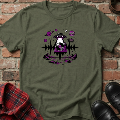 Green t-shirt with alien spaceship graphic on a brick background. Minimalist music apparel by pemuyo.