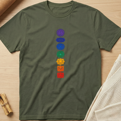 Green t-shirt with colorful chakra symbols on a wooden surface. Minimalist yoga apparel by pemuyo.
