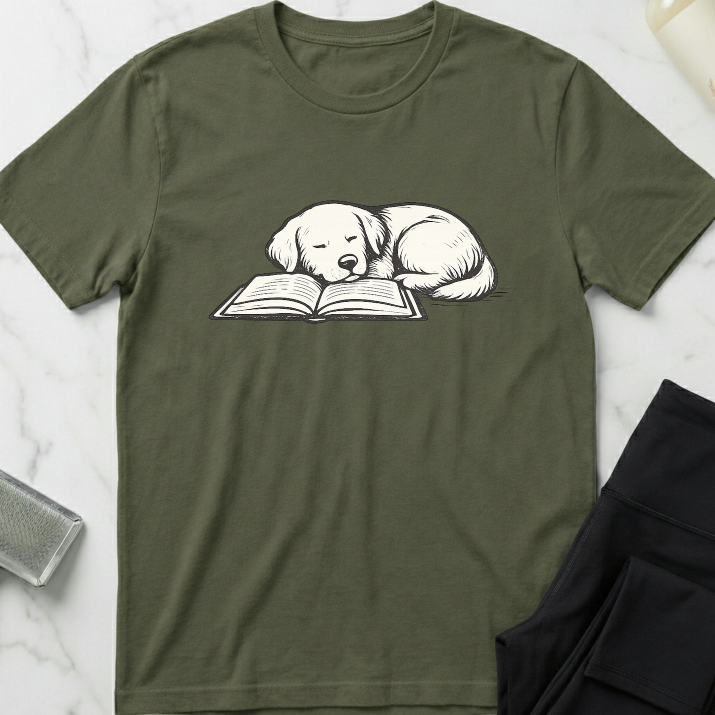 Green t-shirt with a dog reading a book graphic on a marble surface. Minimalist dog apparel by pemuyo.