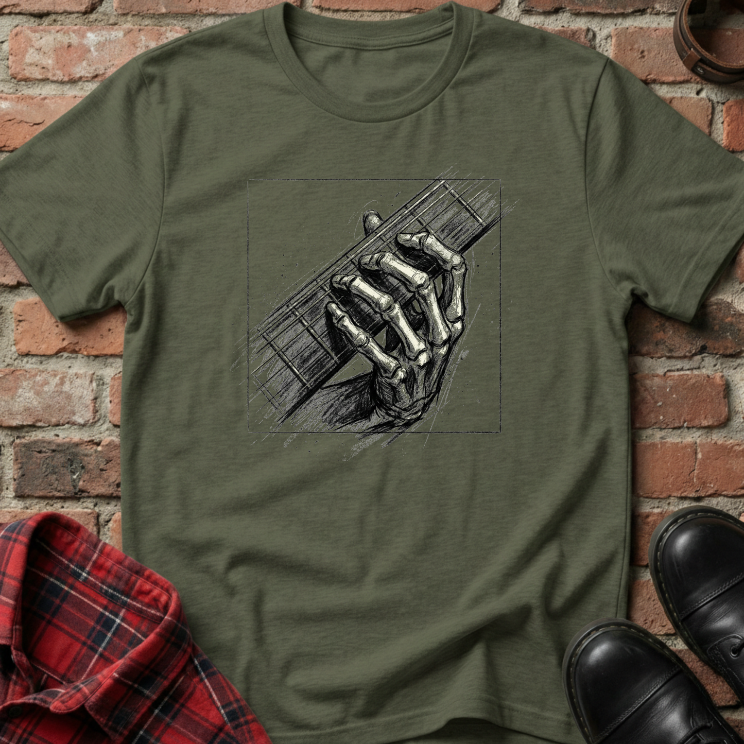 Green t-shirt with skeleton hand holding a guitar graphic on a brick background. Minimalist music apparel by pemuyo.