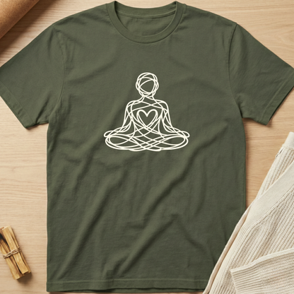 Green t-shirt with a white line art design of a person in meditation on a wooden surface. Minimalist yoga apparel by pemuyo.