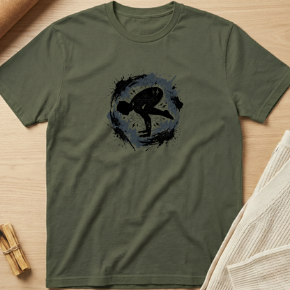 An olive green crewneck t-shirt with a black and blue circular graphic of a martial artist, laid flat on a light wood background with styled props. Minimalist yoga apparel by pemuyo.