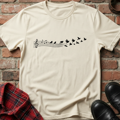 Beige t-shirt with musical note and bird design on a brick wall background. Minimalist music apparel by pemuyo.