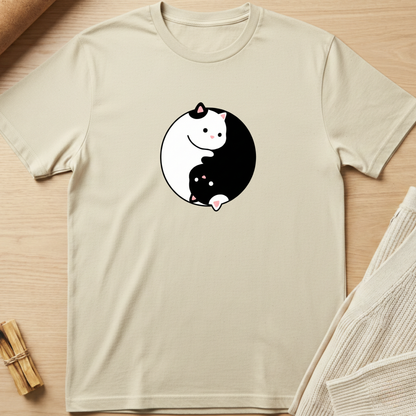 Beige t-shirt with a yin yang design featuring cartoon cats on a wooden surface. Minimalist yoga apparel by pemuyo.
