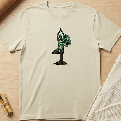 Beige t-shirt with a tree-dwelling figure design on a wooden surface. Minimalist yoga apparel by pemuyo.