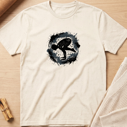 An off-white short-sleeve t-shirt laid flat on a light wood background, featuring a black circular graphic with a stylized human silhouette in the center. Minimalist yoga apparel by pemuyo.